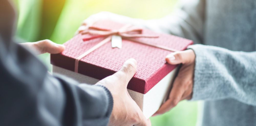 Closeup image of a man giving a woman a gift box