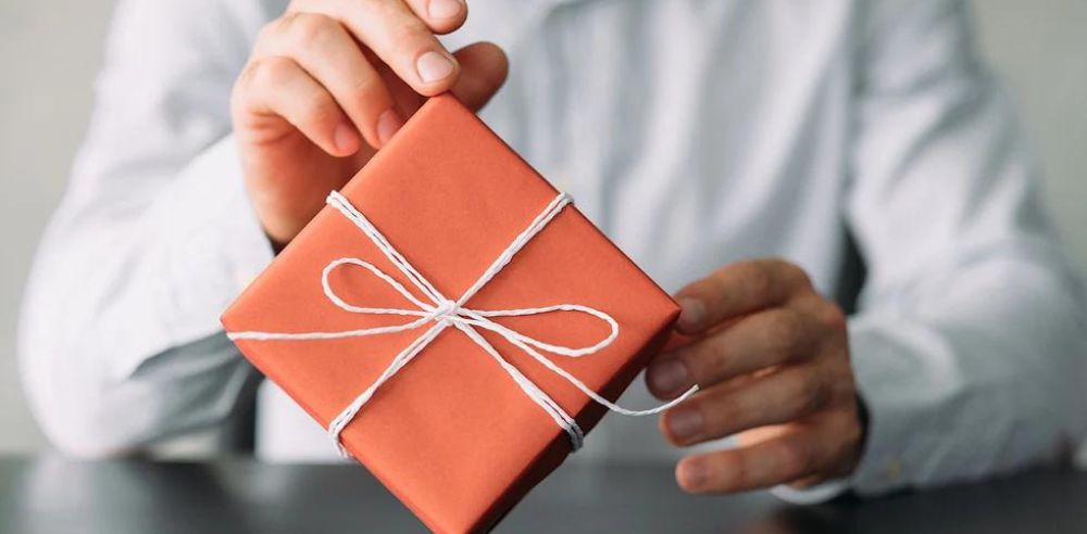 Cropped shot of business man in shirt sitting at desk with red gift box