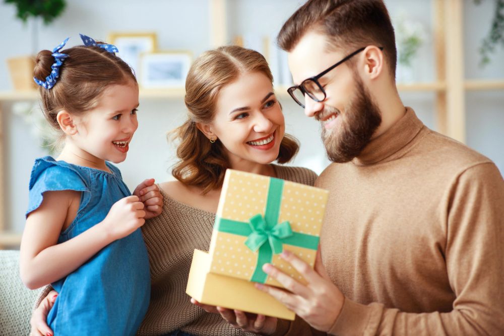 Mom and daughter congratulate dad and give gift .