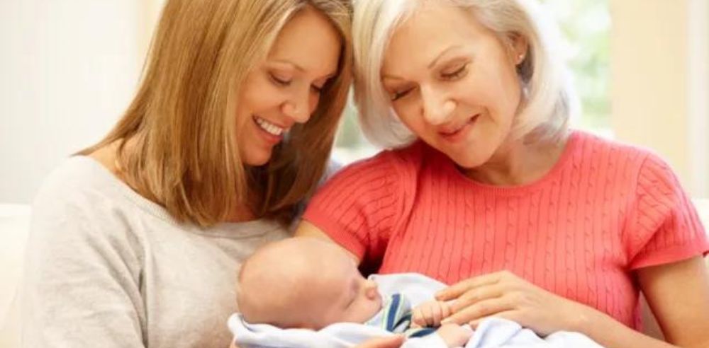 Grandmother holding the baby beside her daughter